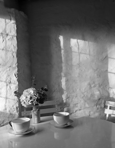 Sala con ventanales y una mesa pequeña, en blanco y negro