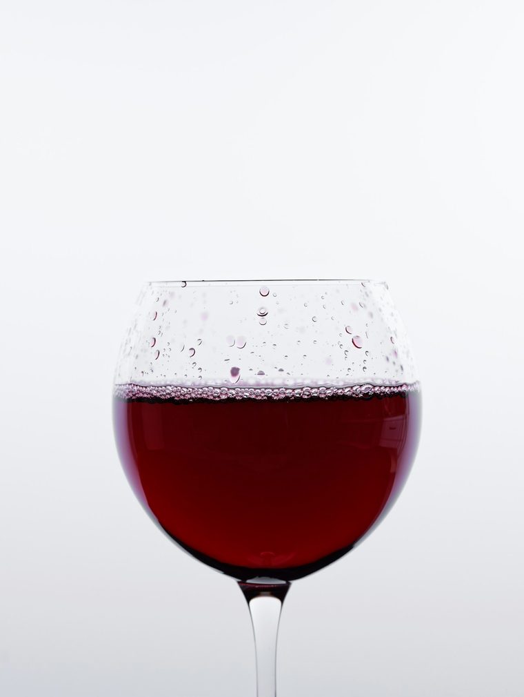 Copa de vino con vino tinto sobre fondo blanco