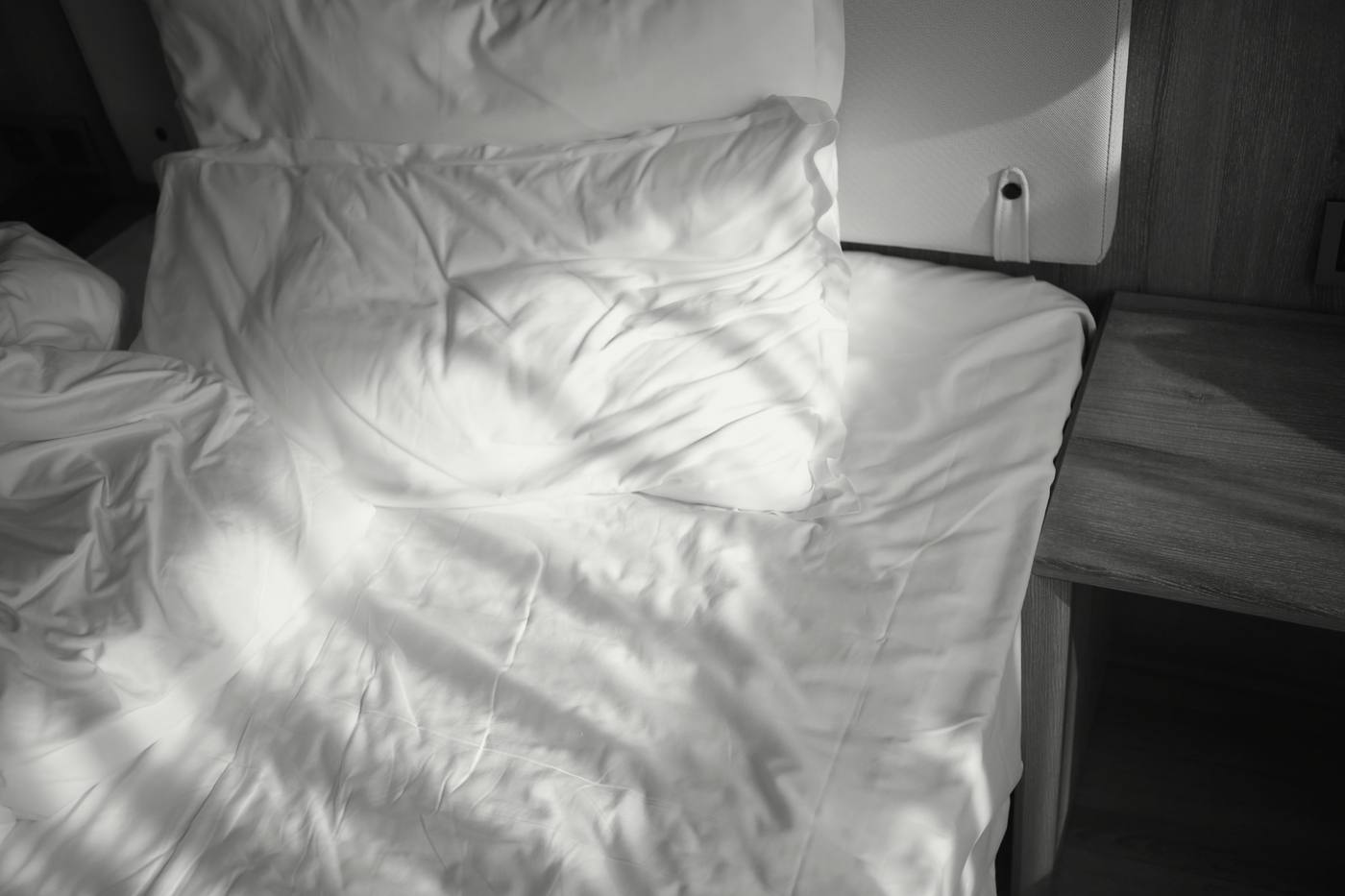 Sábanas revueltas con la luz de la ventana dibujando sombras, en blanco y negro