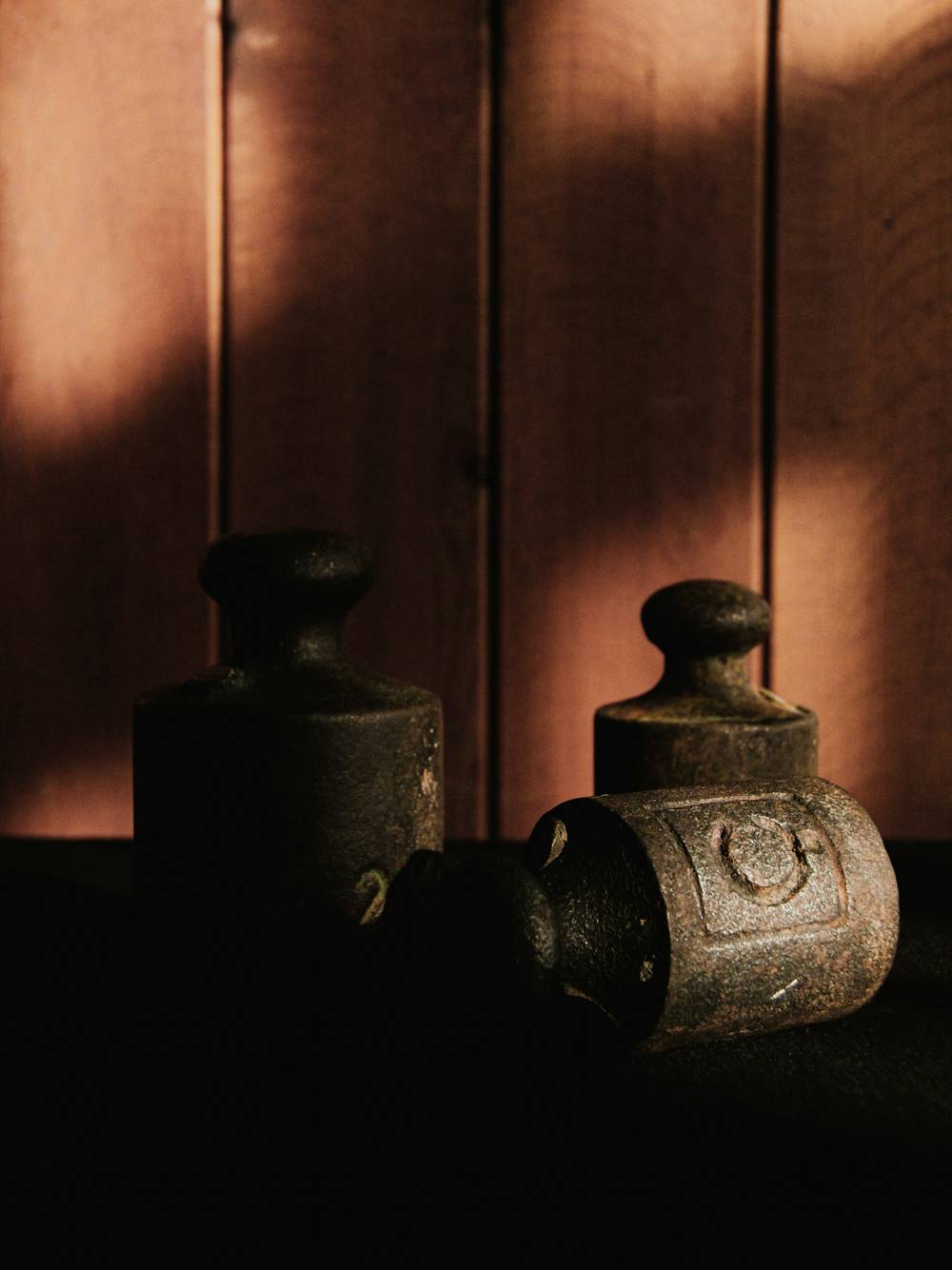 Dos pesas de hierro contra un muro de madera, con sombras alargadas
