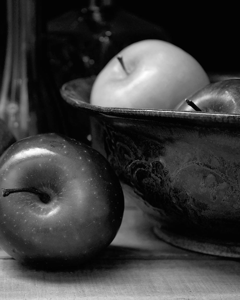 Manzanas y un cuenco labrado en claroscuro, en blanco y negro