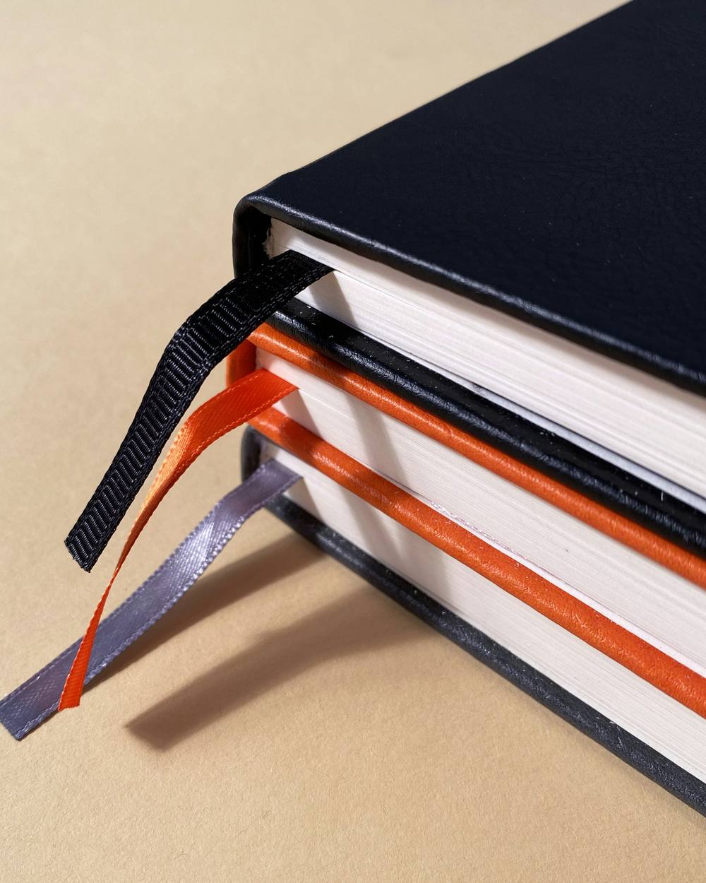 Libros de tapa negra con cintas marcadoras naranja y gris