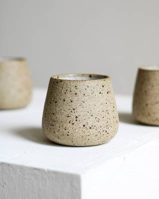 Tazas de gres moteado sobre un bloque blanco