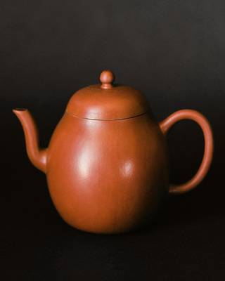 Tetera de barro rojizo sobre un fondo oscuro