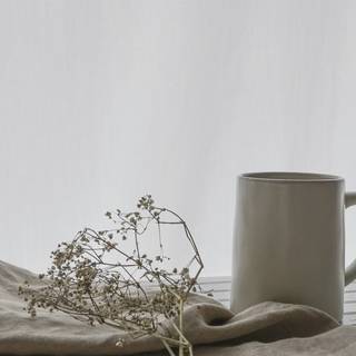 Taza gris junto a un lienzo y ramitas secas