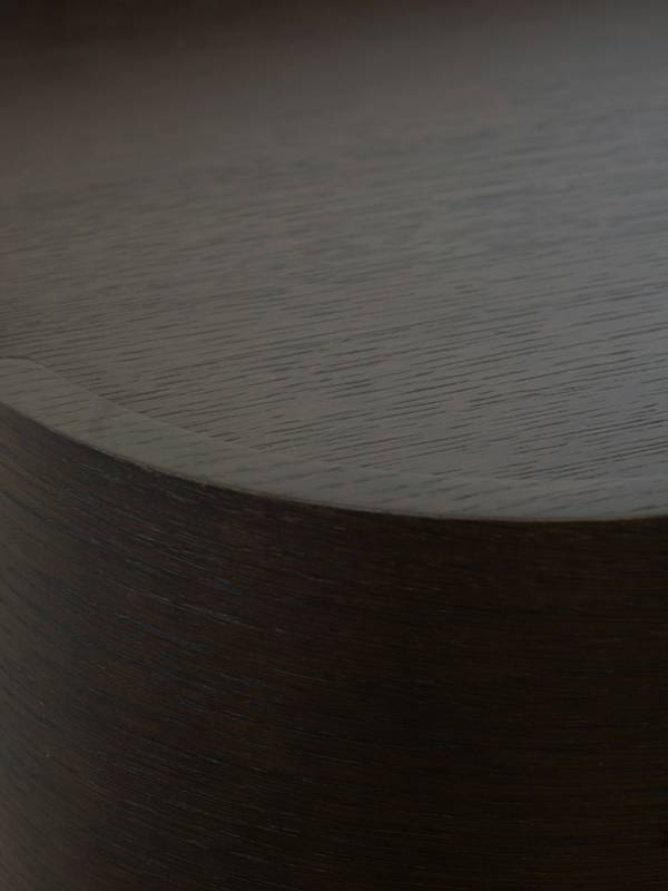 Taburete cilíndrico de madera oscura, visto de cerca