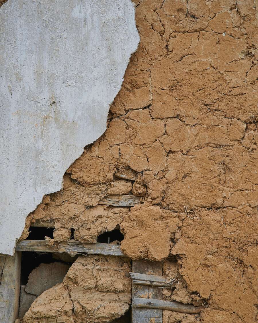Un muro de adobe con el revoque caído y la tierra a la vista
