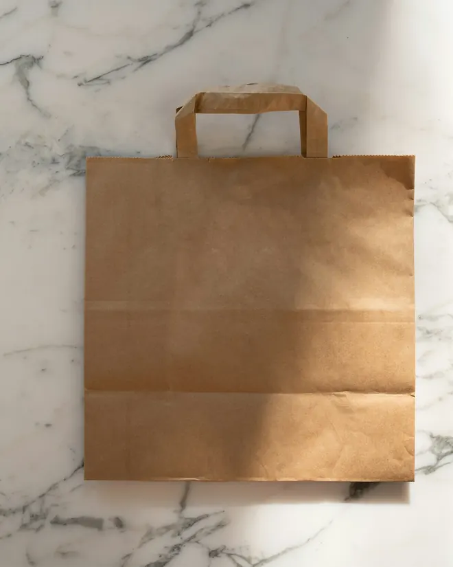 Bolsa de papel kraft apoyada sobre mármol blanco
