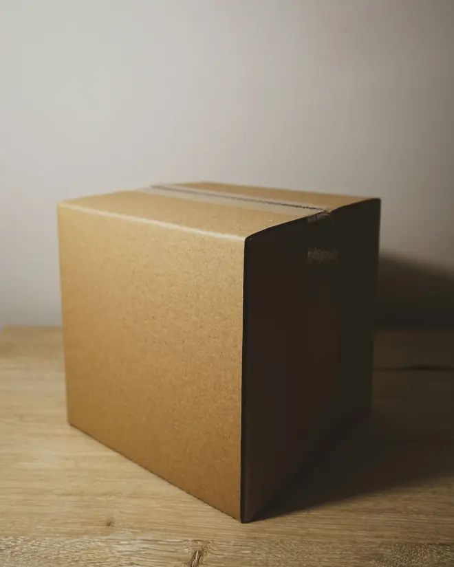 Una caja de cartón cerrada con cinta sobre una mesa de madera