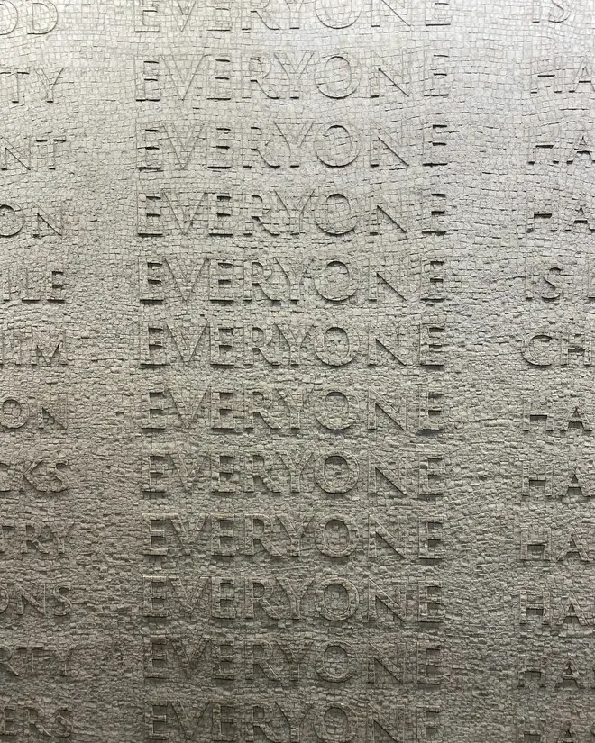 Una palabra repetida en relieve sobre papel, formando una textura de letras