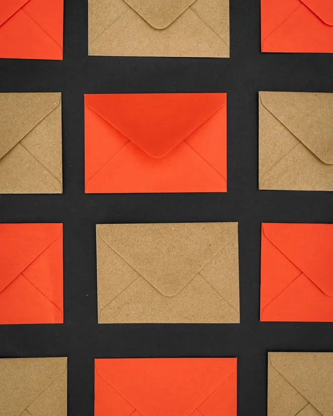 Sobres rojos y de papel kraft dispuestos en cuadrícula sobre fondo negro