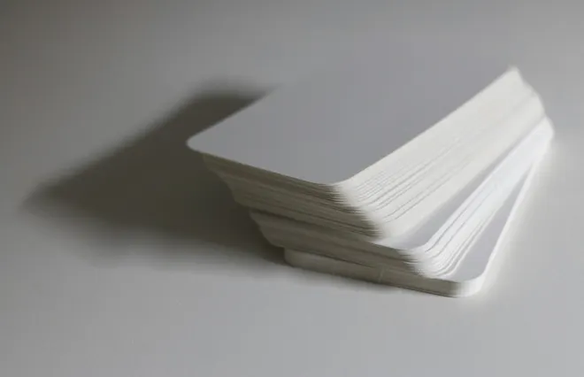 Una pila de tarjetas blancas de esquinas redondeadas sobre una superficie gris