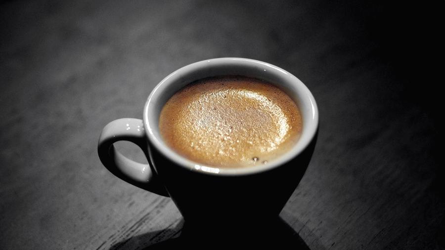Taza de café con crema sobre una mesa oscura