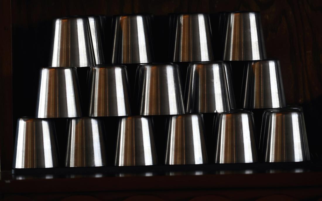 Pila de vasos de acero ordenados en un estante oscuro