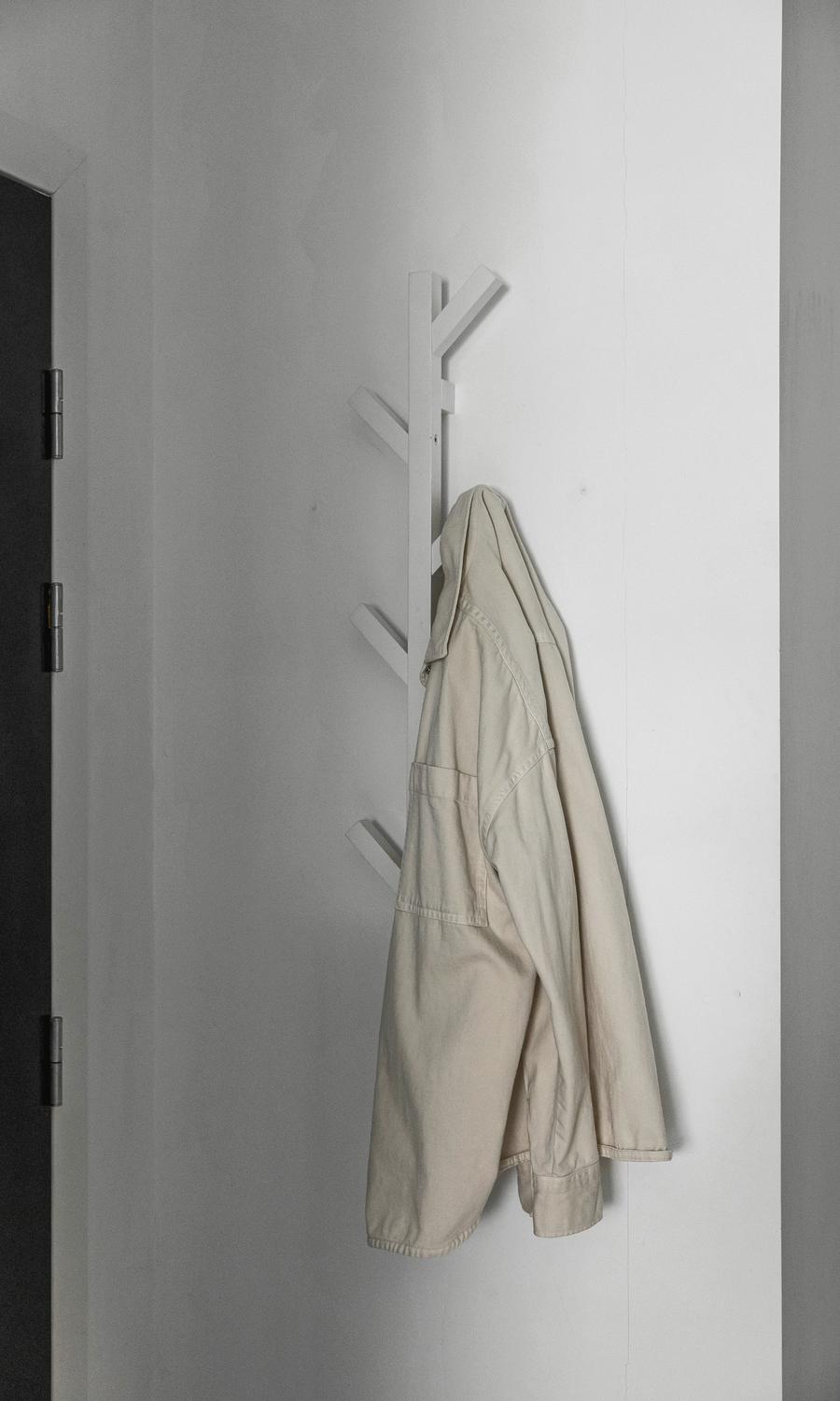Una chaqueta clara colgada de un perchero de pared blanco
