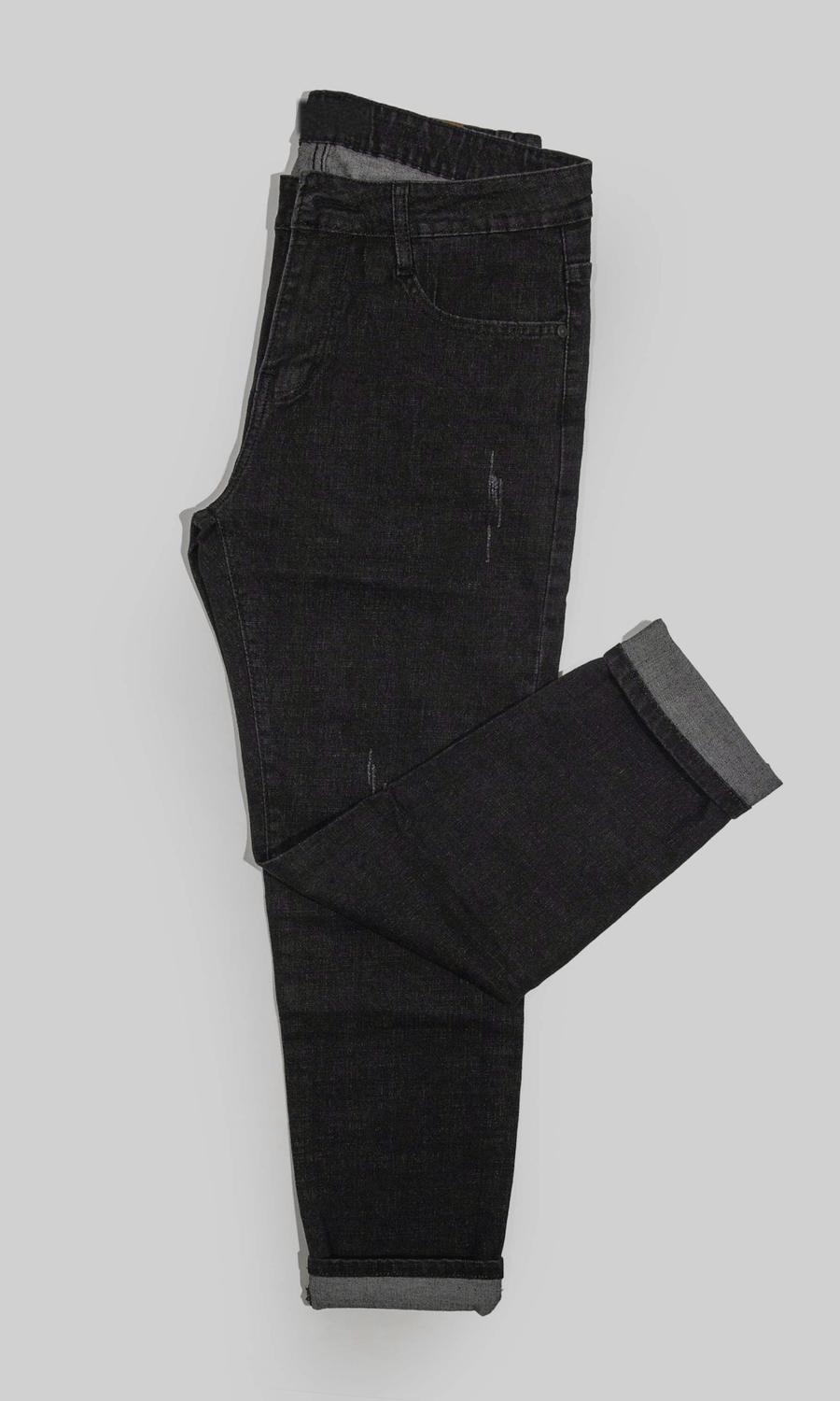 Un pantalón de mezclilla negra doblado sobre un fondo gris claro