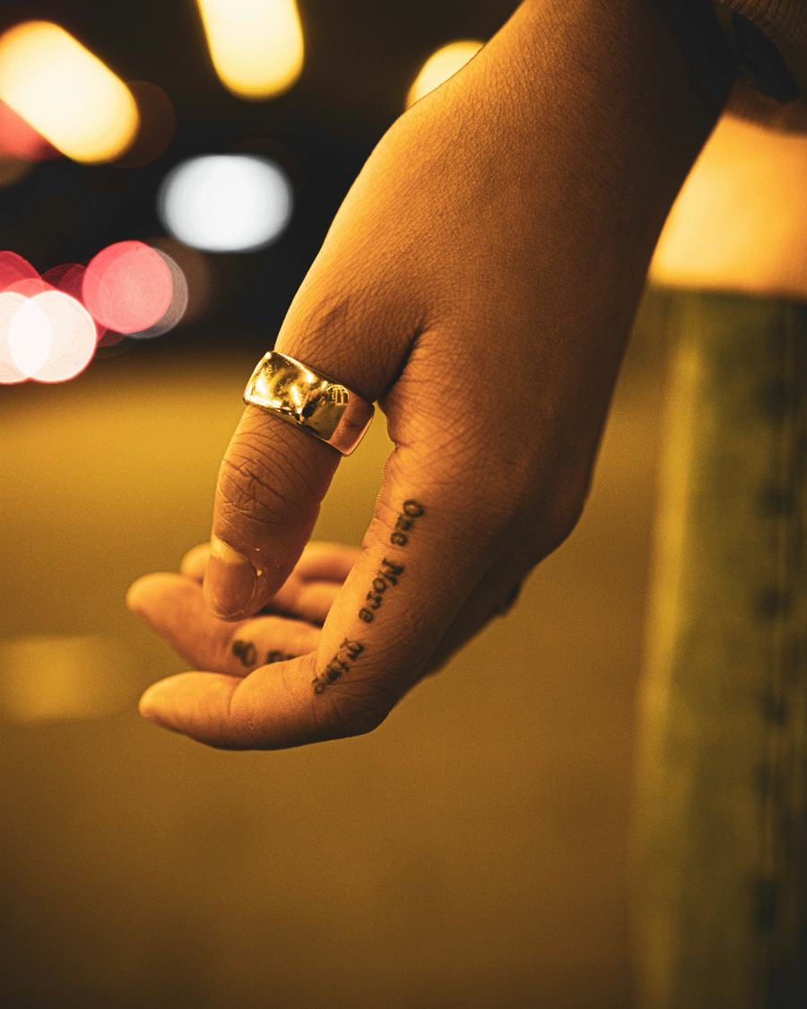 Una mano con un anillo ancho bajo las luces cálidas de la calle