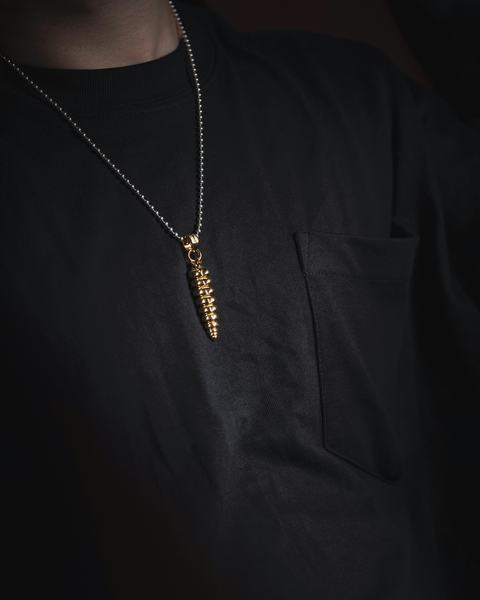 Cadena dorada con un colgante largo sobre una camiseta negra