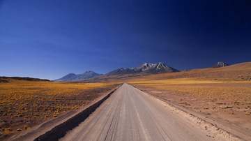 Camino de tierra hacia las montañas bajo un cielo profundo