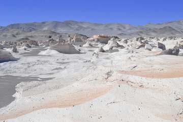 Suelo blanco de sal y piedra bajo las montañas