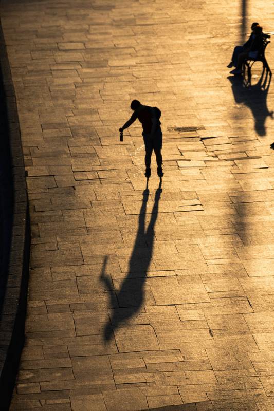 Una figura camina sobre baldosas doradas y proyecta una sombra larga