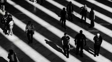 Peatones cruzando franjas de luz y sombra, en blanco y negro