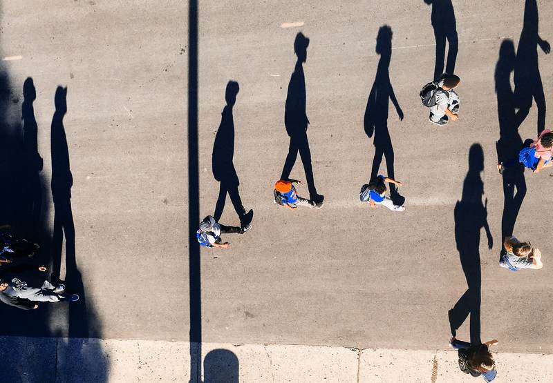 Sombras largas de peatones sobre el asfalto, vistas desde arriba