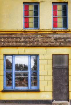 Fachada amarilla con ventanas de marcos azules