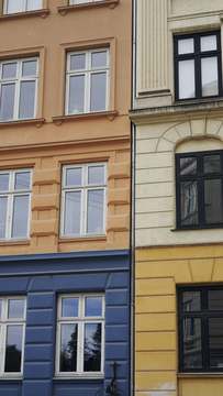 Dos fachadas contiguas, una ocre y otra amarilla, con ventanas blancas