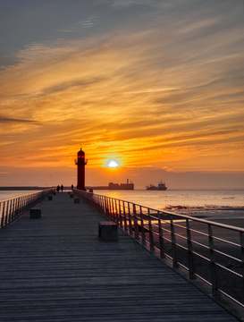 Sol bajo sobre un faro y su espigón