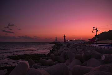 Faro sobre una escollera con cielo rojizo