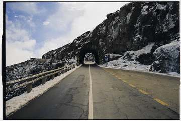 Camino con un túnel excavado en la roca nevada