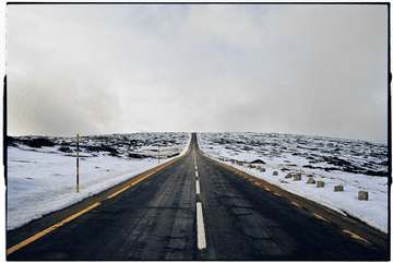 Carretera recta entre nieve y niebla