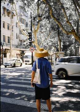 Hombre con sombrero de paja cruzando la calle, de espaldas