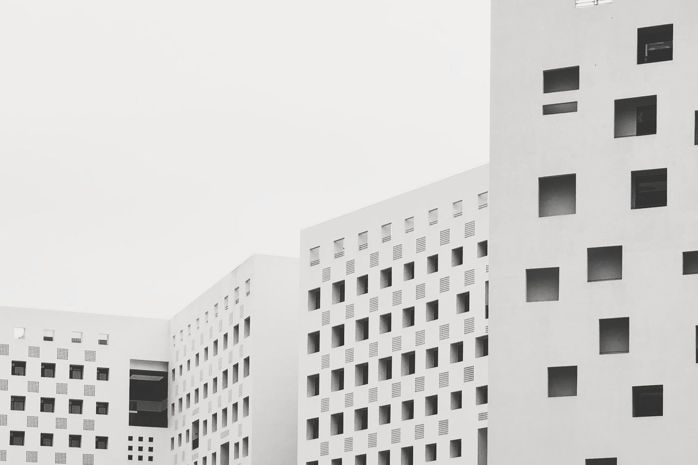 Edificio blanco con ventanas cuadradas de distintos tamaños bajo un cielo claro
