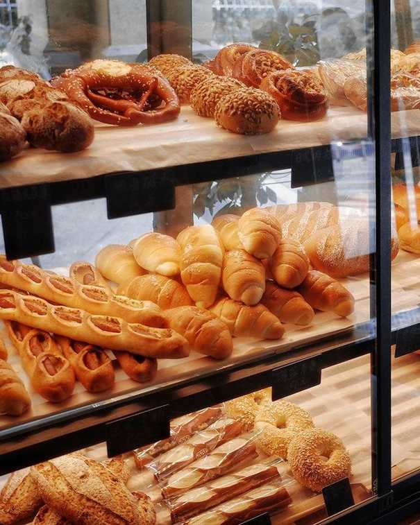 Vitrina de una panadería con bandejas de panes y medialunas recién horneados