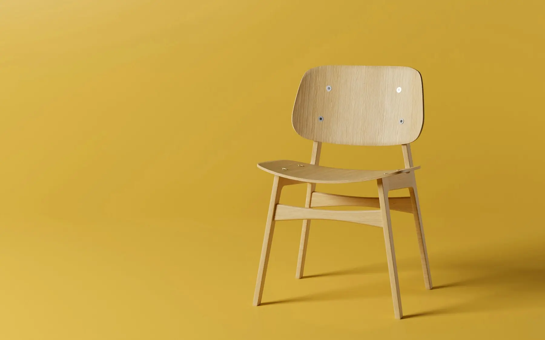 Silla de madera clara sobre un fondo amarillo