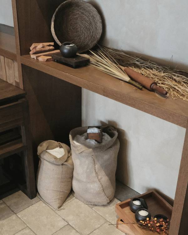 Un rincón de madera con sacos de harina y espigas secas