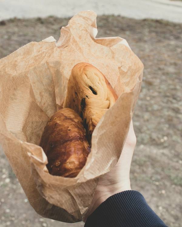 Una mano sostiene una bolsa de papel con dos bollos