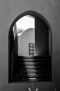 Arco de piedra con una escalera en sombra, en blanco y negro