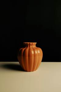 Jarrón de arcilla naranja sobre fondo oscuro