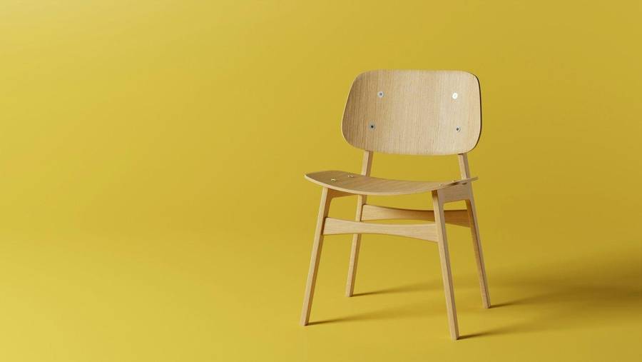 Silla de madera clara sobre un fondo amarillo