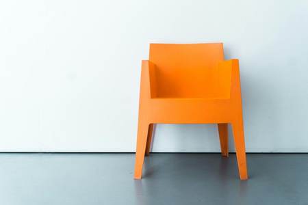 Sillón naranja ante un muro blanco