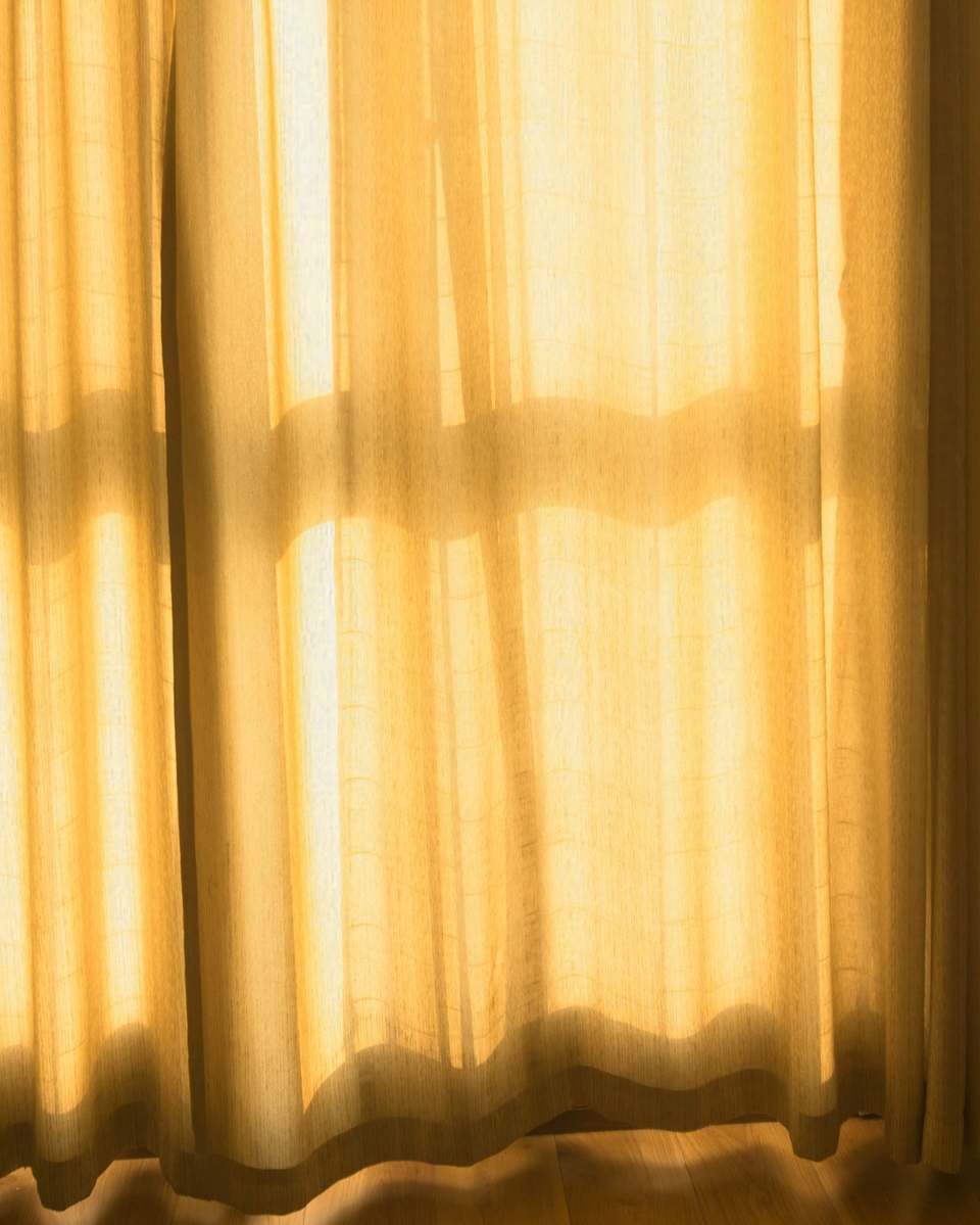 Cortinas de lino doradas por la luz de una ventana