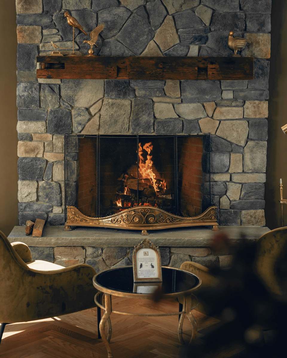 Chimenea de piedra encendida con sillones y una mesa de vidrio