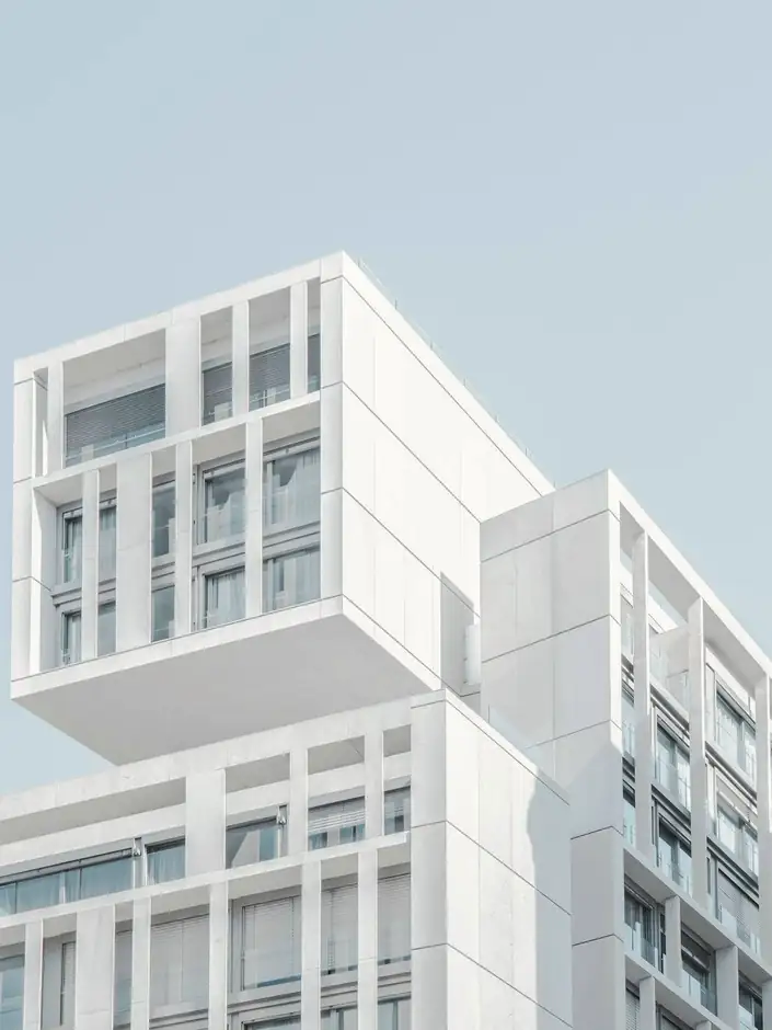 Edificio blanco de ventanas pequeñas bajo un cielo azul pálido