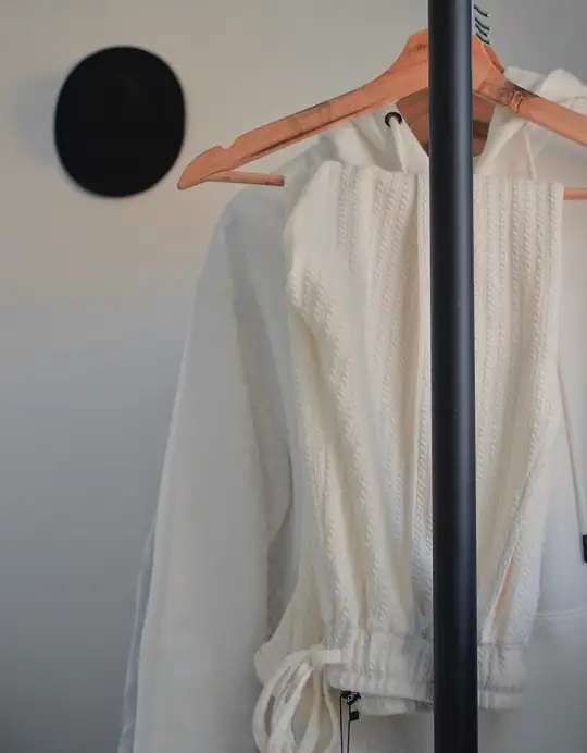 Blusa blanca de mangas atadas colgada de un perchero de madera