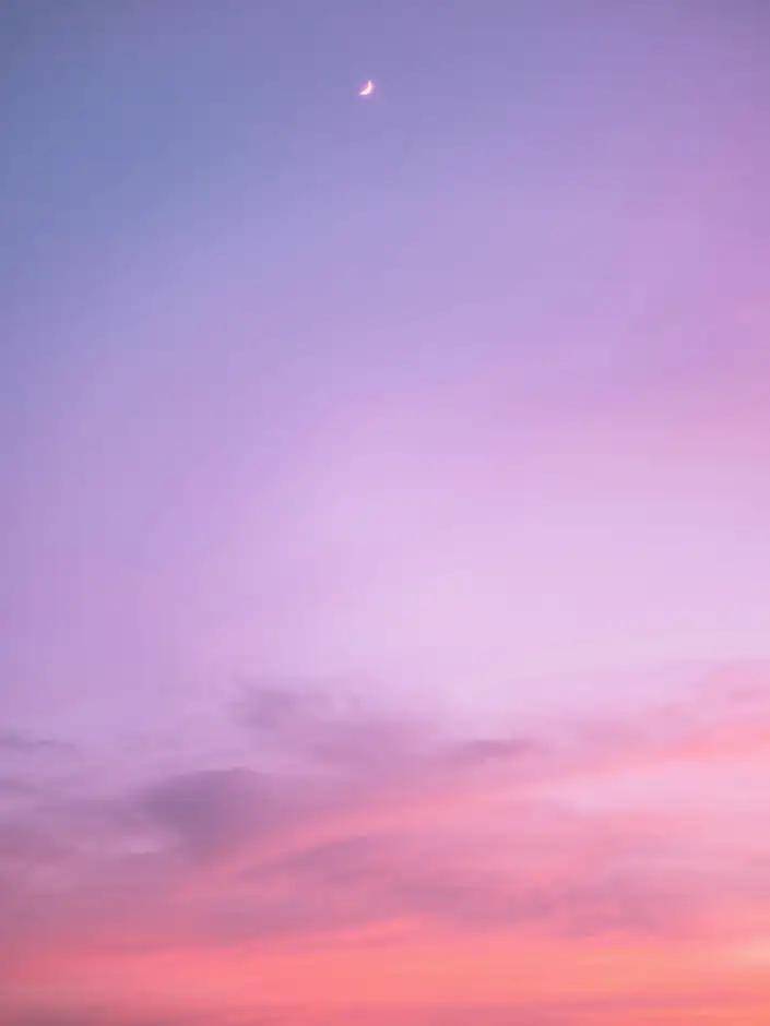 Cielo violeta que baja al rosa, con una luna delgada