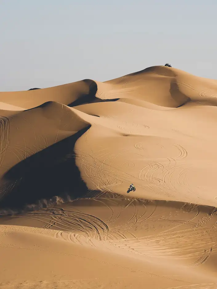 Dunas con un camino de huellas y una figura diminuta