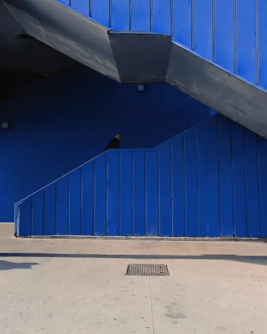 Escalera bajo un muro azul, con un cielo despejado